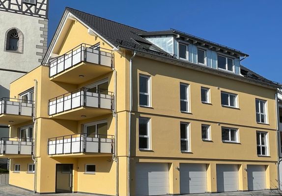 Mehrfamilienhaus mit Balkonen und Garagen – Pfeil Bauträger