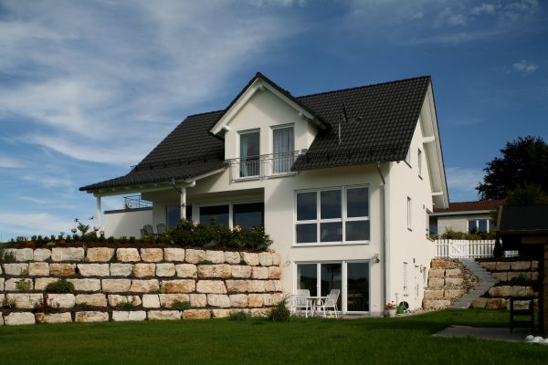 Einfamilienhaus in Hanglage mit Natursteinmauer – Pfeil Bauträger